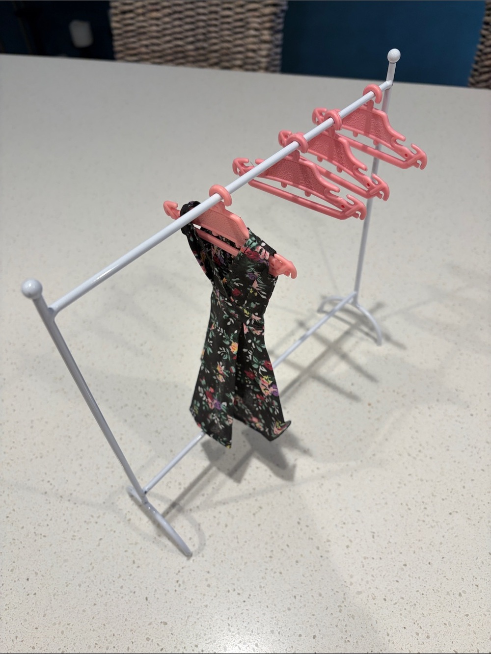 1/6” scale Barbie clothes rack with four hangers.